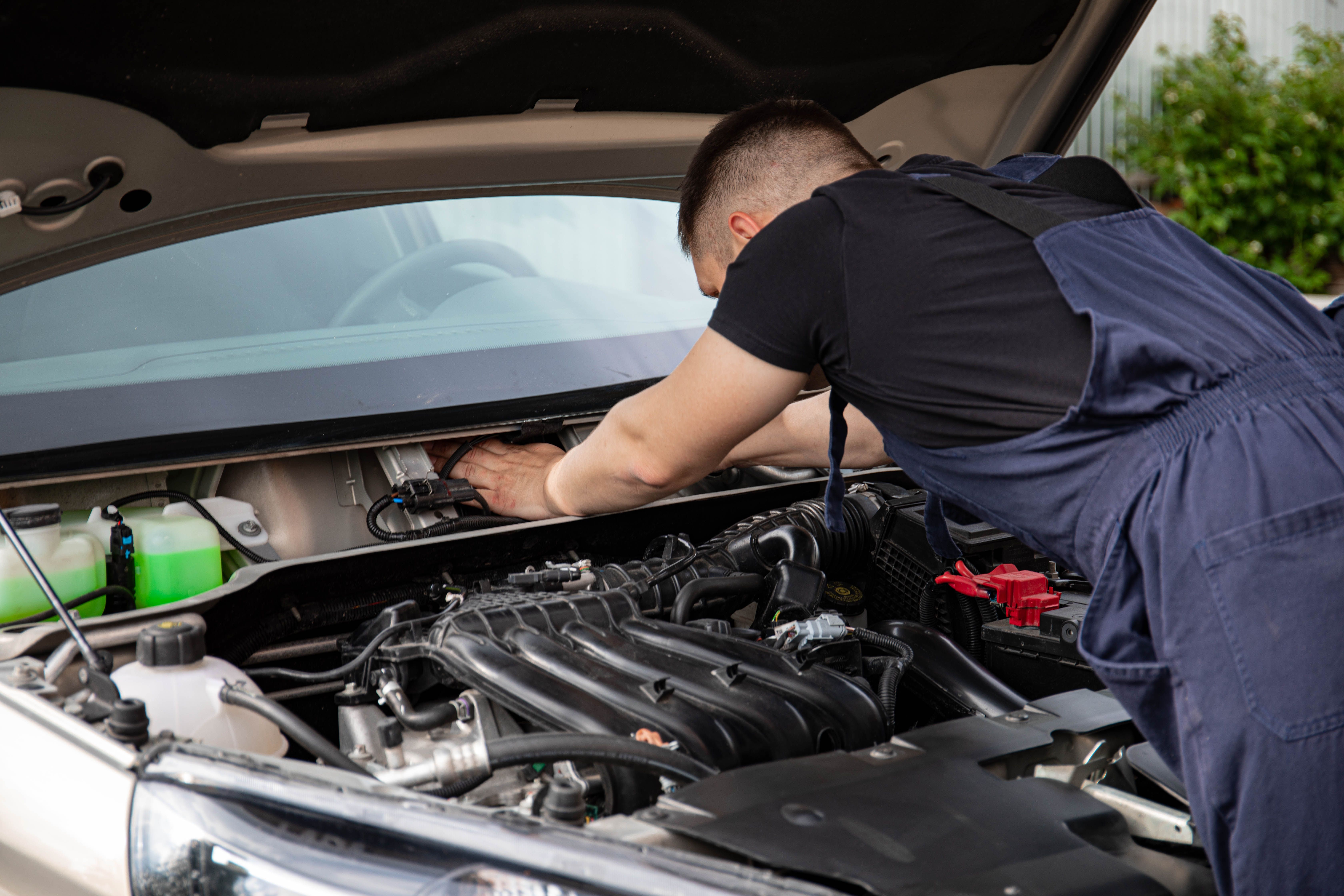 Mechanic inspecting a car exhaust heat shield causing rattling when accelerating
